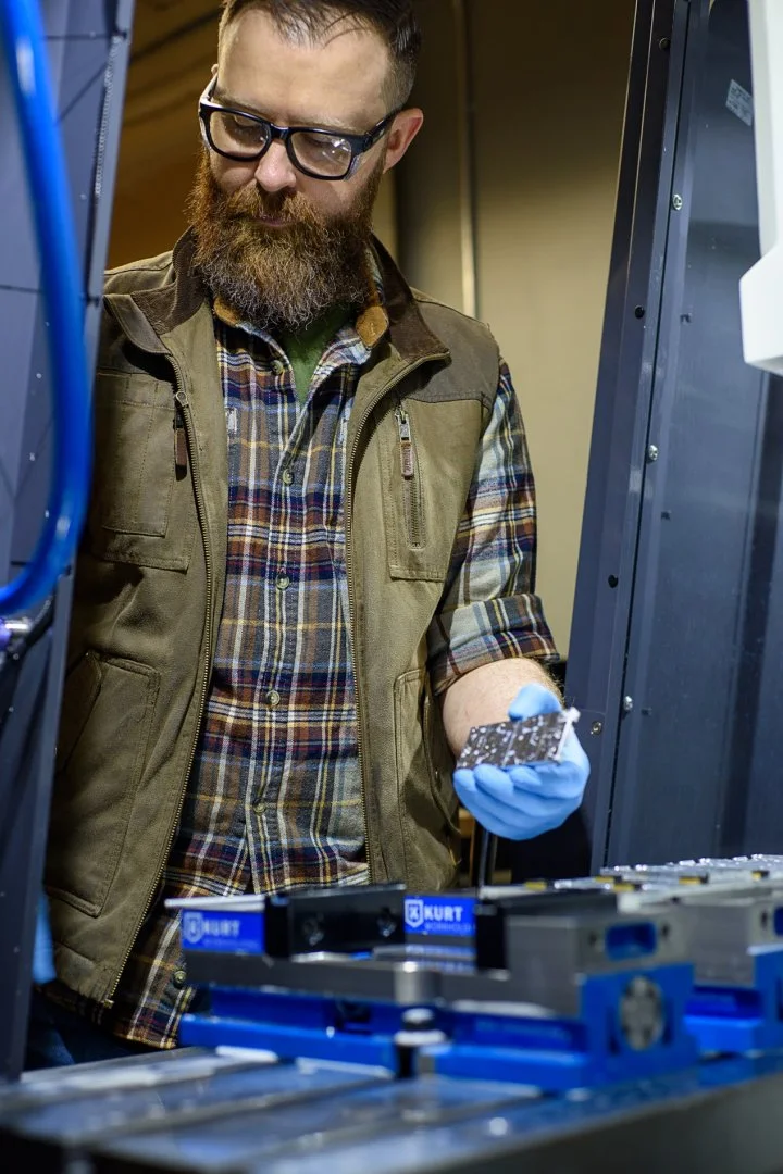 Machinist holding a small precision-machined component in gloved hands
